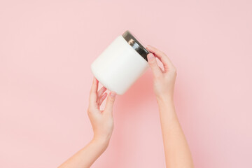 Hands hold white bottle with nourishing mask for applying to hair or skin. Beauty and spa, cosmetics