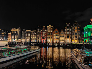 Amsterdam night cityscape over the water. Famous Dutch dancing houses reflecting in the canal