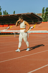 Naklejka premium A sportswoman is walking on stadium and protects herself from sun.