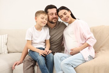 Happy pregnant woman spending time with her son and husband at home