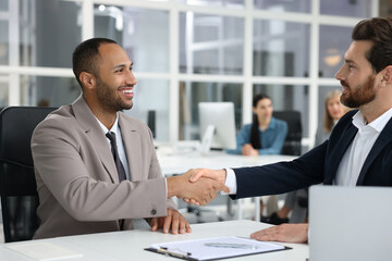 Fototapeta premium Lawyer shaking hands with client in office, selective focus