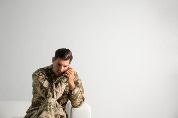 Stressed military officer sitting on sofa against white background. Space for text