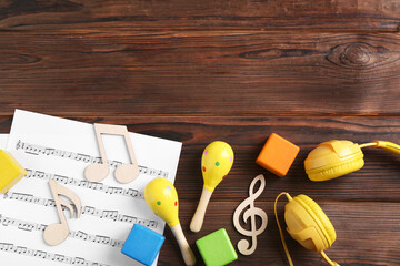 Baby song concept. Wooden notes, music sheet, headphones and toys on table, flat lay. Space for text