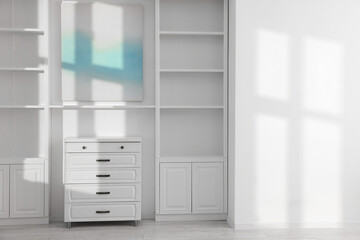 Shelving unit, chest of drawers and shadows on wall