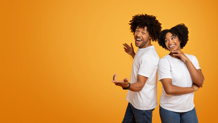 Positive millennial african american couple posing on orange