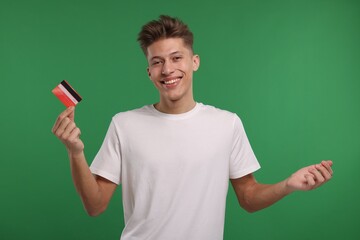 Happy man with credit card on green background