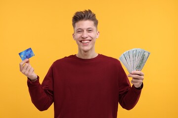 Happy man with dollar banknotes and credit card on yellow background