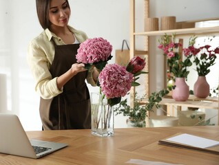 Florist with beautiful flowers at table in workshop