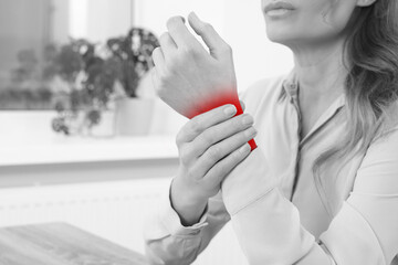 Woman suffering from rheumatism at home, closeup. Black and white effect with red accent in painful...