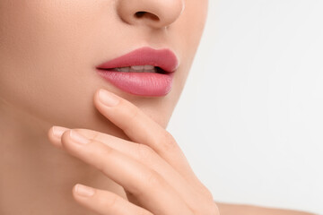 Young woman with beautiful full lips on white background, closeup