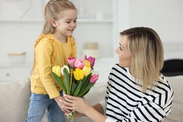 Fototapeta na wymiar Little daughter congratulating her mom with bouquet of beautiful tulips at home. Happy Mother's Day