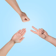 People playing rock, paper and scissors on light blue background, top view