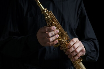Naklejka premium soprano saxophone in hands on a black background