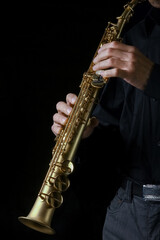 Fototapeta premium soprano saxophone in hands on a black background