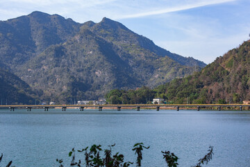 Un pueblo situado en las montañas, cerca de un enorme embalse y del puente que lo cruza, con...