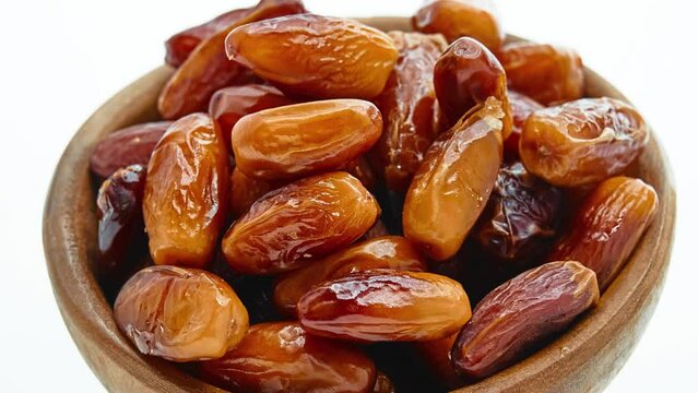 Circular motion Sweet dates in wooden bowl isolated on white background.