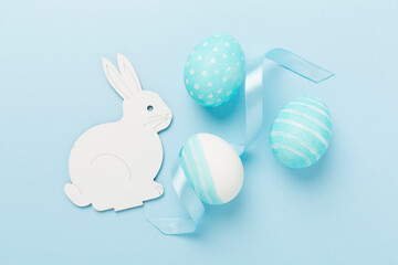 Blue easter eggs with bunny on color background, top view