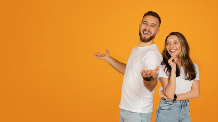 Smiling young man and woman in casual white t-shirts and blue jeans posing playfully