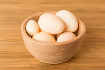 Beige easter eggs in bowl on wooden table
