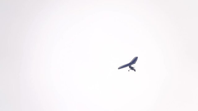 A small automated paraglider with a motor is flying through the sky.