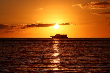 Sunset over ocean with ship