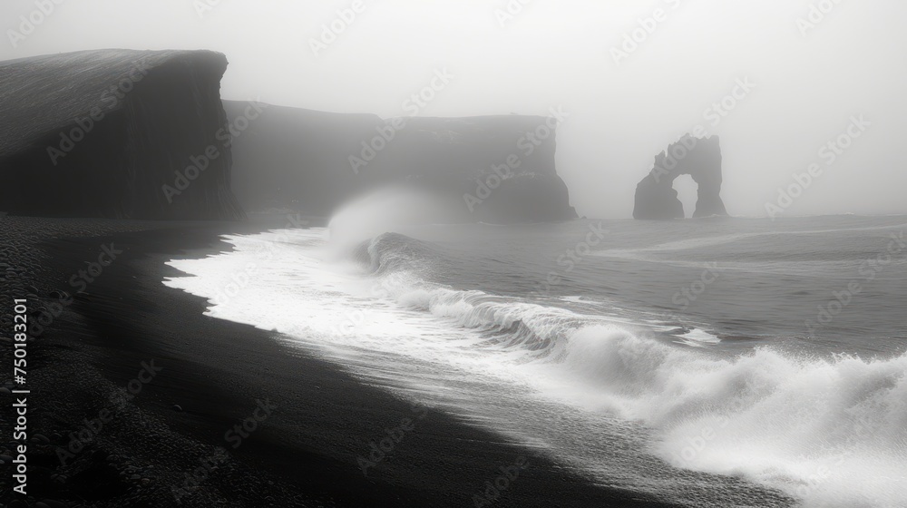 Poster a black and white photo of a beach with waves crashing in front of a rock formation on a foggy day w