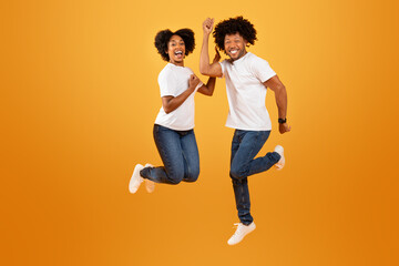 Excited millennial african american couple jumping in the air