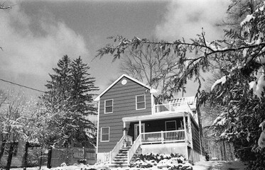 suburban house and driveway covered with snow after the snow storm in late winter in black and white