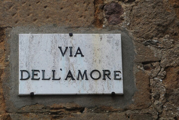 Marble street sign of the Via dell'Amore (Love street) in Pienza, Tuscany, Italy on brown grunge old stone wall