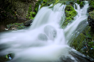 Flowing water in waterfall between rocky stream in the mountains - 750193212