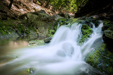 Waterfall between rocky stream in the mountains - 750193404