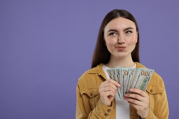 Woman with dollar banknotes on purple background, space for text