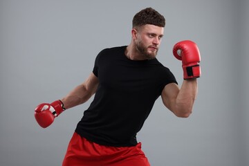 Man in boxing gloves fighting on grey background