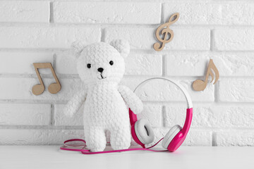 Baby songs. Toy bear and headphones on white wooden table and notes
