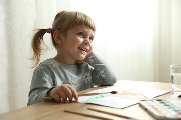 Naklejka premium Cute little girl drawing at wooden table indoors. Child`s art