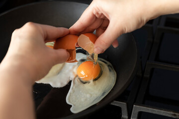 Close-up shot of a woman breaking an egg and preparing scrambled eggs for breakfast
