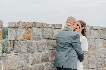 the bride and groom embrace near the stone wall