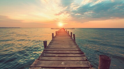 Wooden pier stretching into calm seas at sunrise - An expansive view of a wooden pier reaching towards a sunrise over calm seas, embodying new beginnings and hope