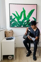 Latin man playing acoustic guitar at home