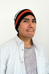 Latin man wearing a beanie on the white background making facial expressions
