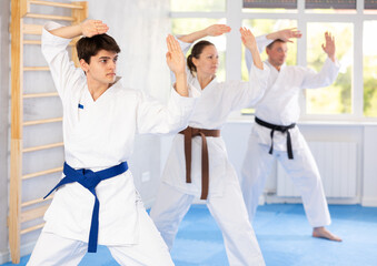 Three athletes have taken starting position and studying and repeating sequence of punches and...