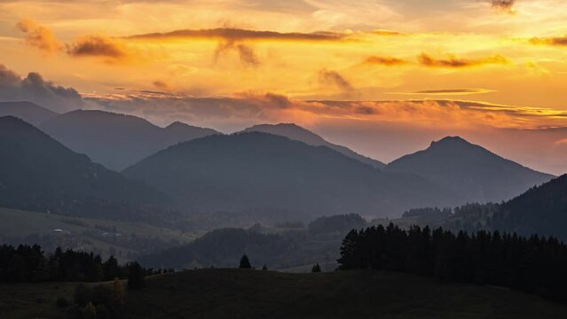 Clouds sky moving fast over forest mountains landscape at golden sunset time lapse
