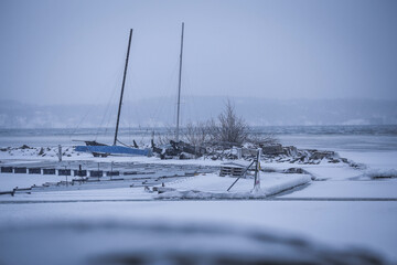 A few old sail boats sit at a l lake covered by ice in the middle of winter off Stockholm, Sweden. 