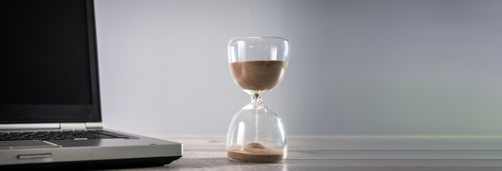 Laptop and hourglass on the table