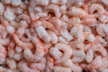 Lots of frozen shrimp for background use, closeup, top view. Seafood on the counter. Fish market. Peeled boiled shrimps