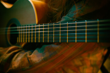 Cinematic coloured .Guitar detail dark light. Play Music. Close up  classic guitar indoors