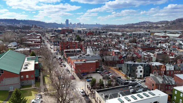 An early Spring aerial establishing shot of Pittsburgh's Lawrenceville district. The city skyline in the far distance.  	