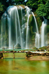 Ban Gioc Tranquility: Vertical Bliss of Cascading Water, Wooden Bridge, and Verdant Nature in Vietnam's Enchanting Falls