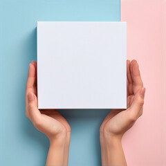 **Image Art** : A minimal flat lay of a white box held by two hands against a blue and pink background. - obrazy, fototapety, plakaty