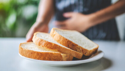 Sliced white bread on plate, woman's hand on stomach. Symbolizing gluten intolerance and dietary awareness